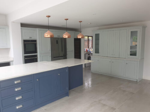 Modern kitchen installation with island and copper pendant lights by Art & Build Ltd construction company