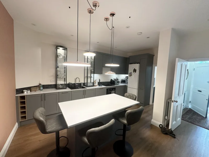 Angled view of a contemporary grey kitchen with island seating and access to the entrance hall in Holland Park