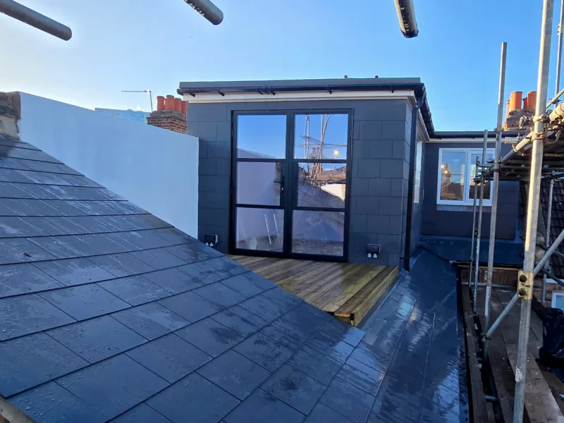 Completed L-shaped loft conversion with slate roof, French doors and roof terrace in Croydon, by experienced builders based in Croydon