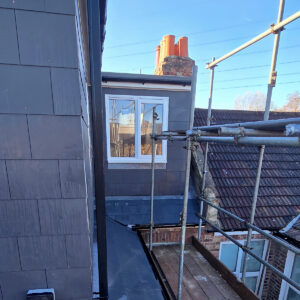Narrow space with scaffolding beside a slate-clad rear dormer in Croydon, by the Croydon-based team at Art & Build Ltd