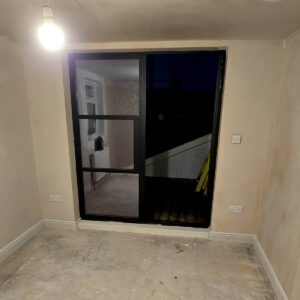 Newly plastered loft room with black-framed French doors leading to the roof terrace, by Croydon loft conversion builders Art & Build Ltd