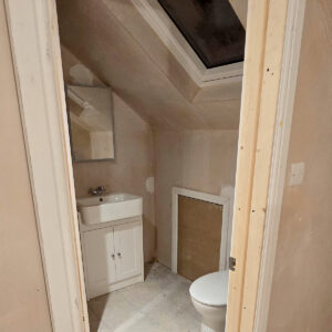 Entrance to a new loft en-suite beneath a sloping roof with fitted sanitaryware, by the Croydon-based team at Art & Build Ltd
