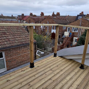 Timber roof terrace with glass balustrade overlooking neighbouring rooftops, by Art & Build Ltd, a Croydon-based construction company