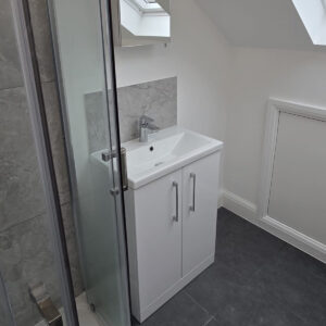 Loft en-suite bathroom with a glass shower enclosure, vanity unit and roof window in Southwark
