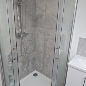 Corner glass shower enclosure with grey tiled walls in a completed Southwark loft en-suite