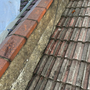 Close view of the existing roof tiles and adjoining brickwork before roof reconstruction