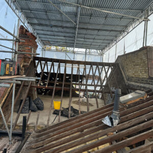 Wide view of the stripped existing roof framing before structural steel installation