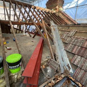Red structural steel beams laid across the stripped roof ready for loft conversion installation