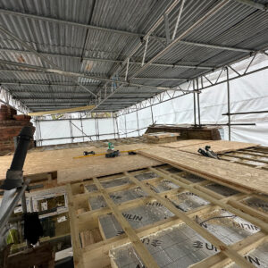 Wide view of insulation installed between the flat roof joists of an L-shaped dormer loft conversion