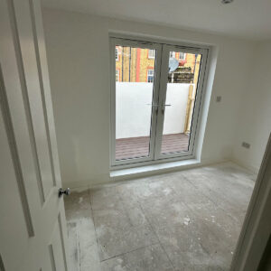 New loft bedroom with glazed double doors opening onto a roof terrace in Southwark