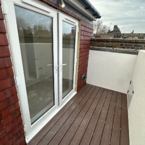Completed loft roof terrace with composite decking, white walls and glazed bedroom doors in Southwark