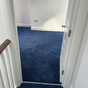 Completed loft landing with blue carpet leading into a new bedroom in Southwark