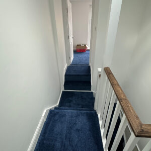 Completed loft hallway with blue carpet and bespoke staircase in Southwark