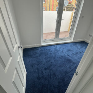 Completed loft bedroom with blue carpet and glazed doors leading onto the roof terrace in Southwark