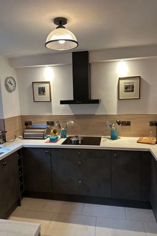 Modern kitchen installation in Croydon with black extractor, induction hob and stone-effect worktops