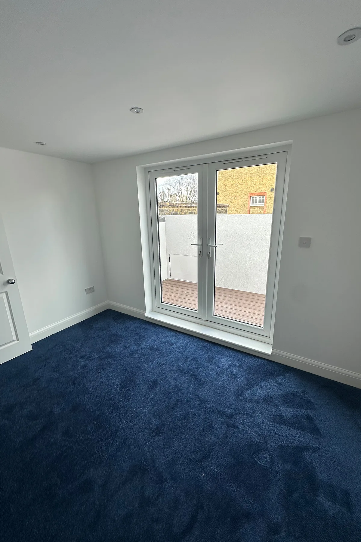 Finished loft bedroom with roof terrace doors after rear dormer loft conversion in Croydon