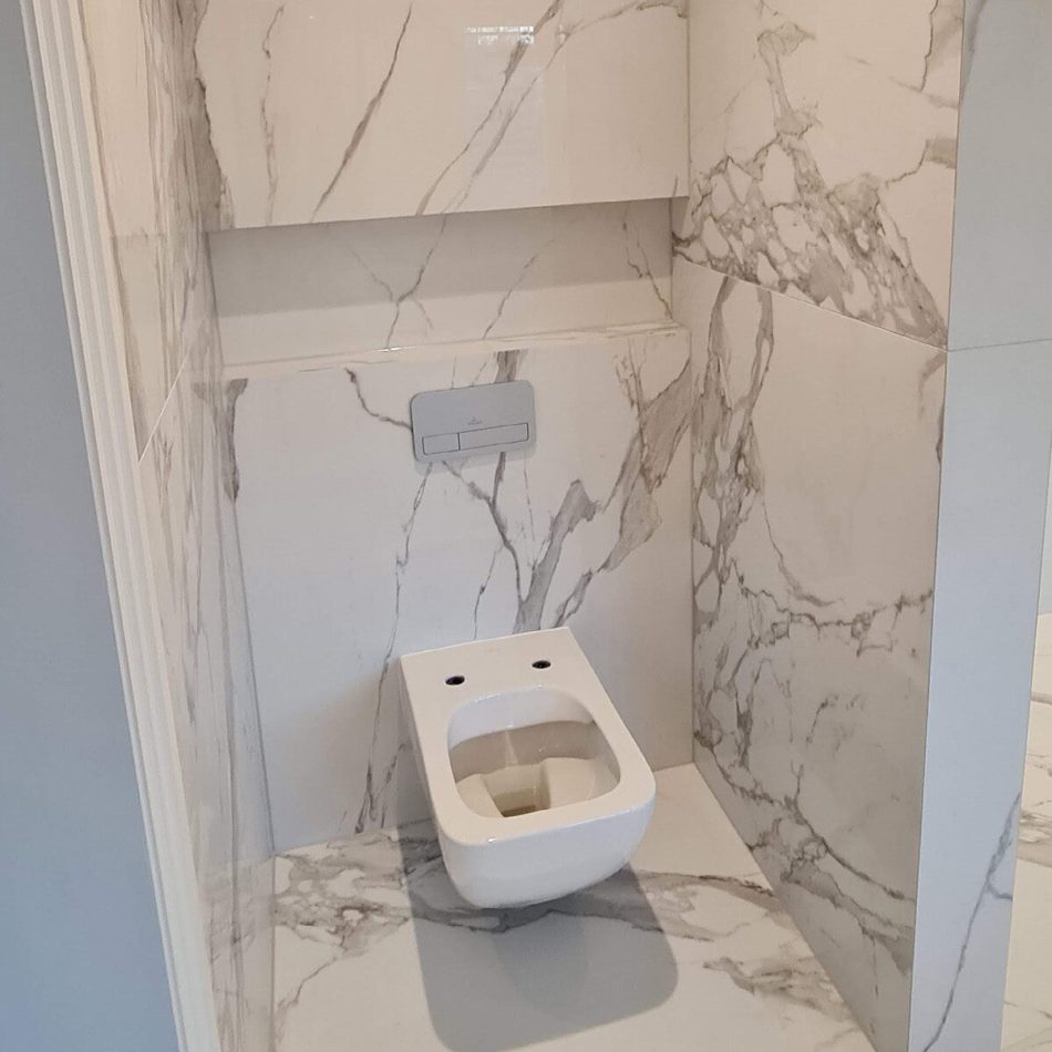 Wall-hung toilet installed in a luxury marble-effect bathroom in Weybridge