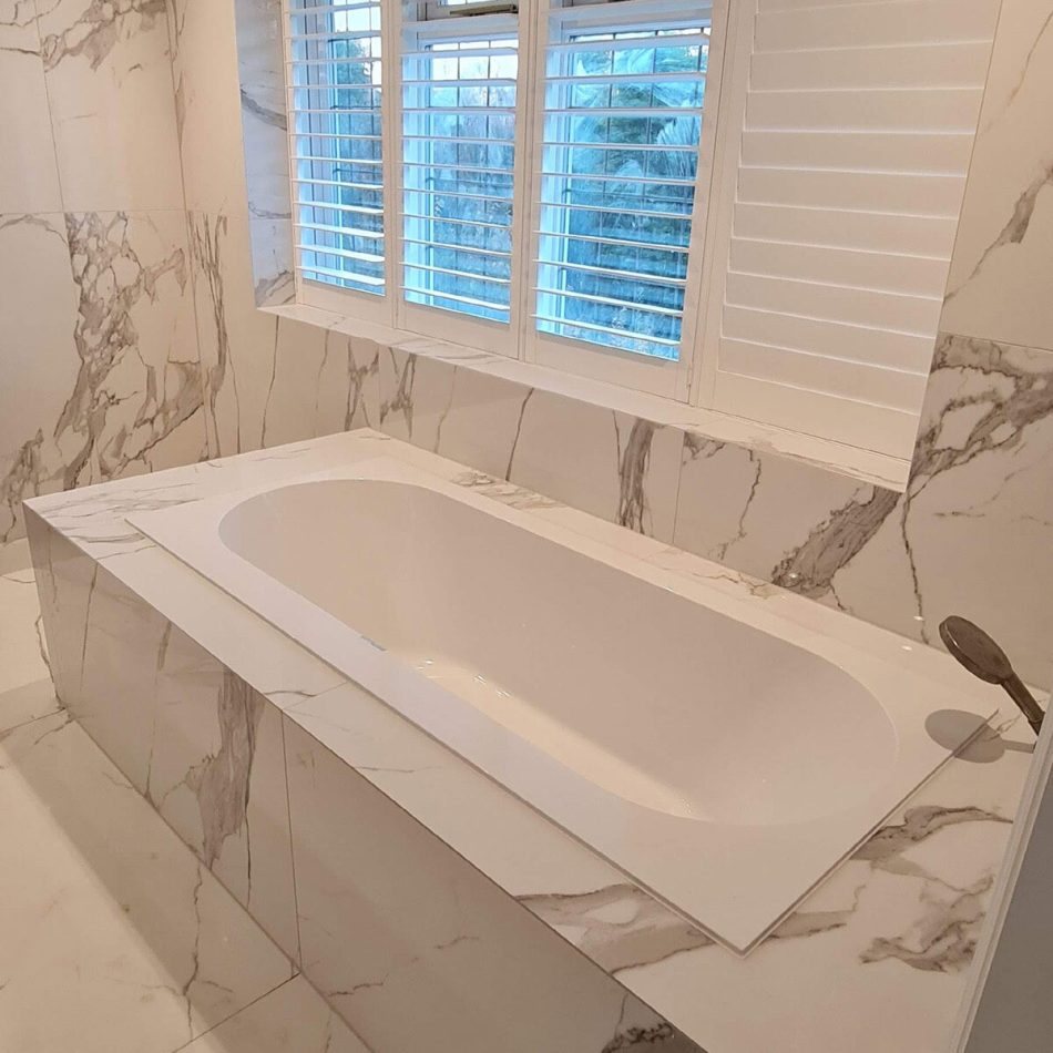 Built-in bath with marble-effect tiled surround installed by Croydon-based builders Art & Build Ltd in Weybridge